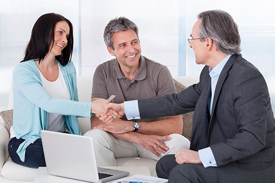 A man and woman shaking hands with an older gentleman.