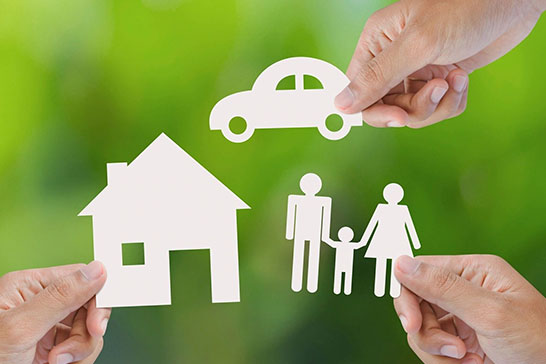 A person holding paper cut outs of a house, car and family.