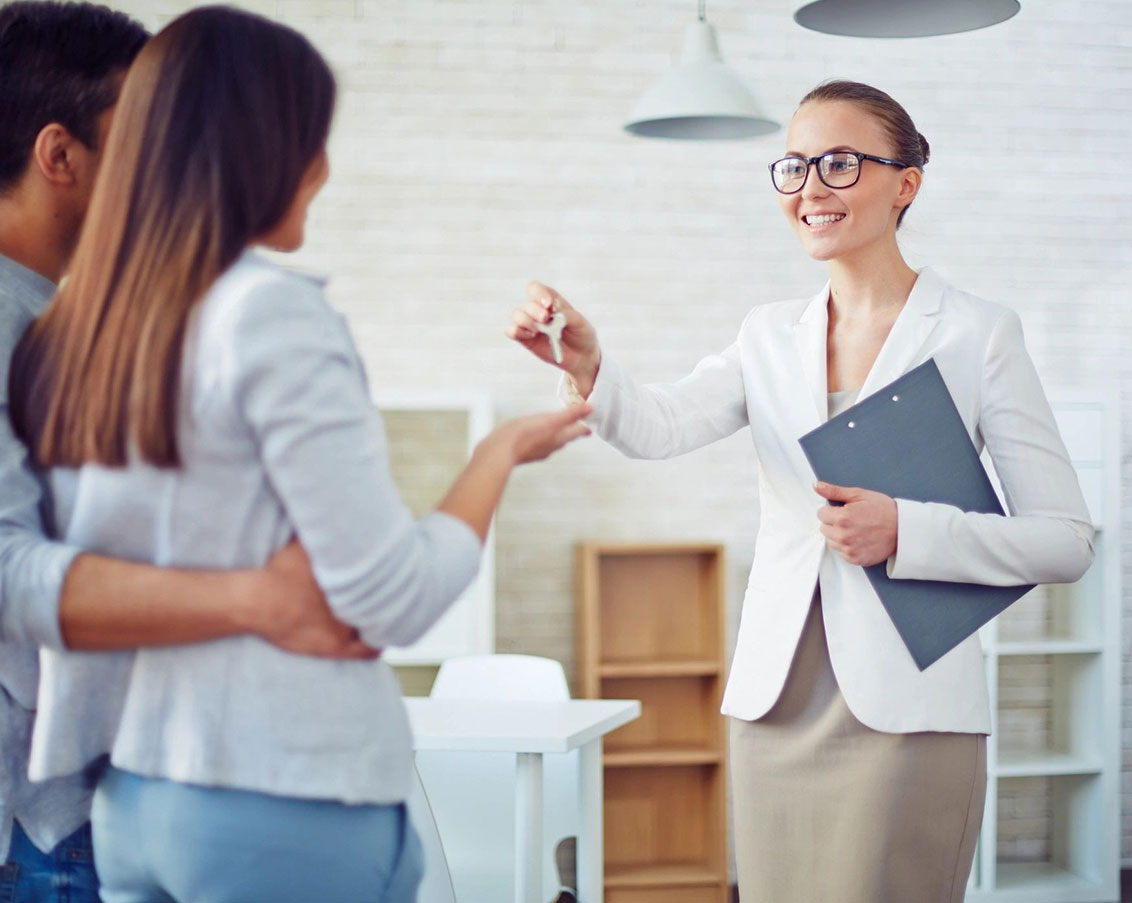 A woman holding keys to another person in front of them.