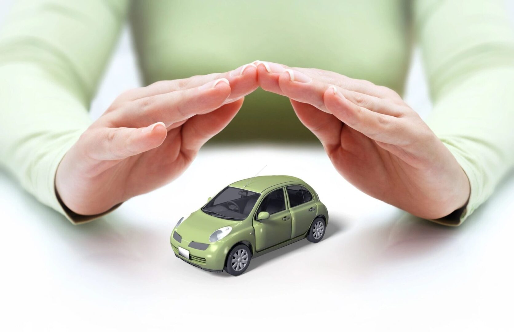 A person is holding their hands over a green car.
