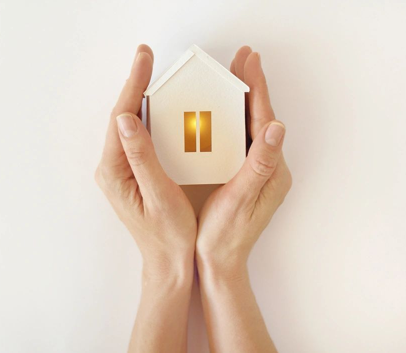 A person holding a small house in their hands.