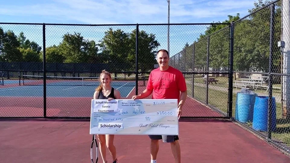 A man and woman holding a cheque for $ 1 0, 0 0 0.
