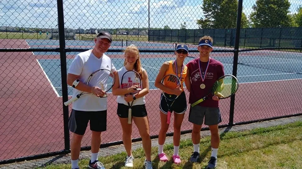 A group of people standing on top of a tennis court.