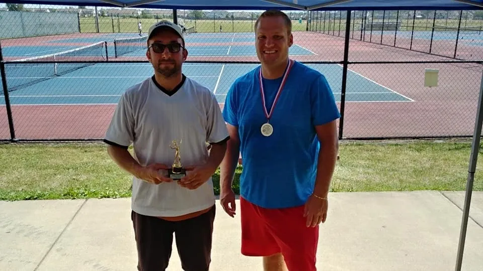 Two men standing next to each other holding a trophy.