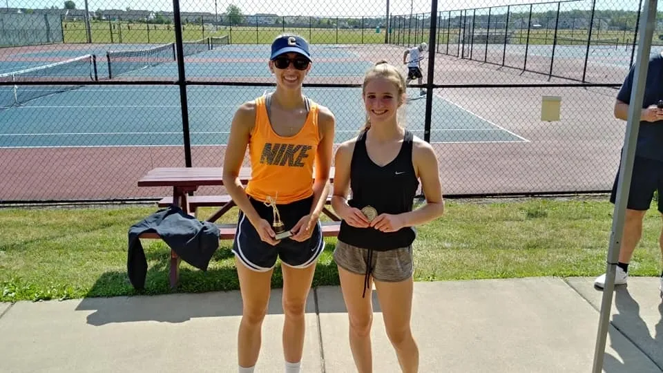 Two women holding tennis rackets on a court.