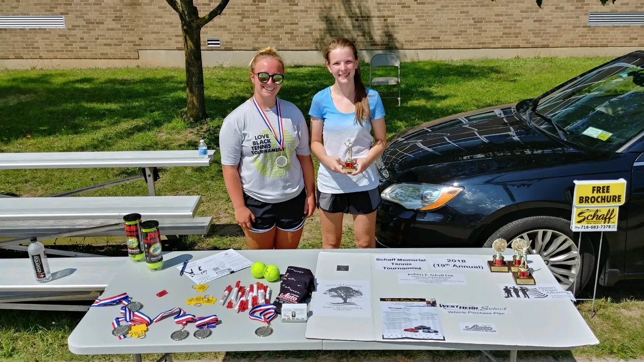 Two girls standing next to a table with prizes.