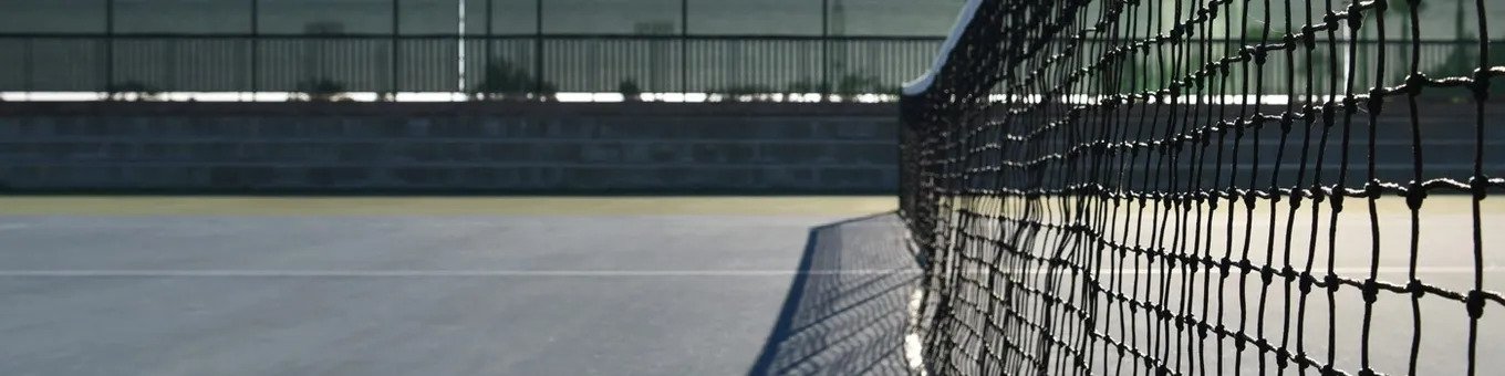 A tennis court with a net and fence.